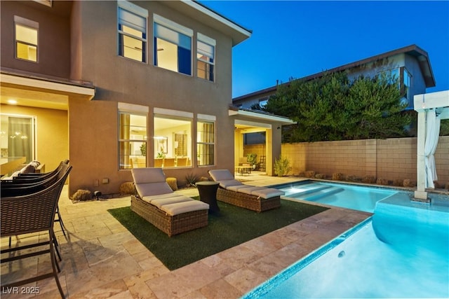 rear view of property featuring a fenced in pool and a patio area