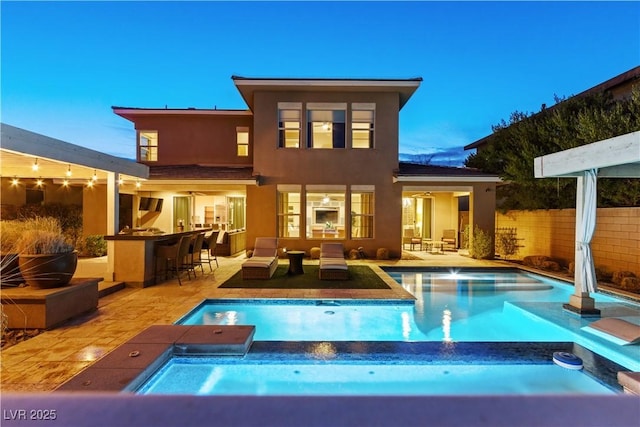 back house at dusk featuring a fenced in pool, a patio area, and an outdoor bar