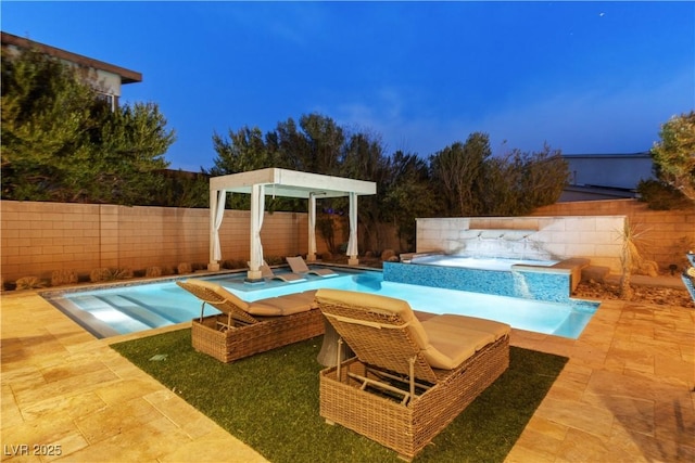 pool at dusk featuring a patio area, pool water feature, and an in ground hot tub