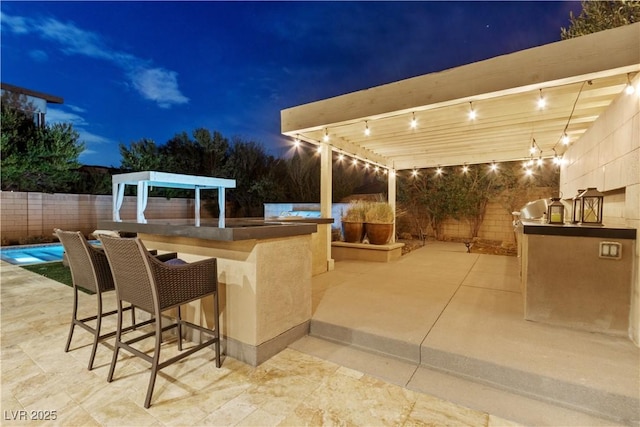 patio at twilight with an outdoor kitchen and exterior bar