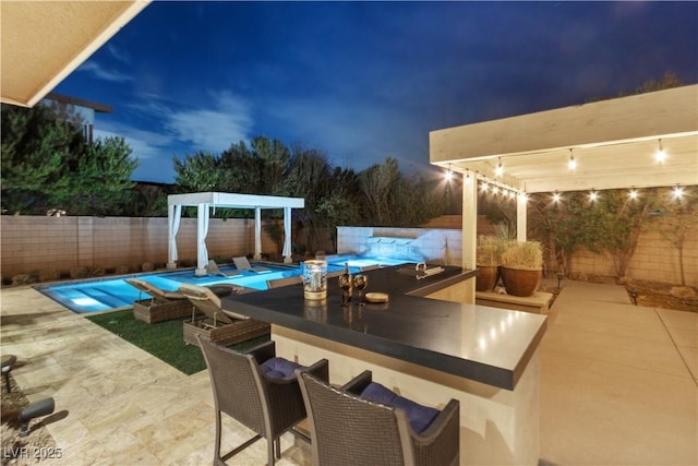 pool at twilight featuring a patio and an outdoor bar