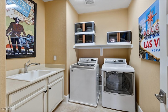 clothes washing area with light tile patterned flooring, cabinets, sink, and washing machine and dryer