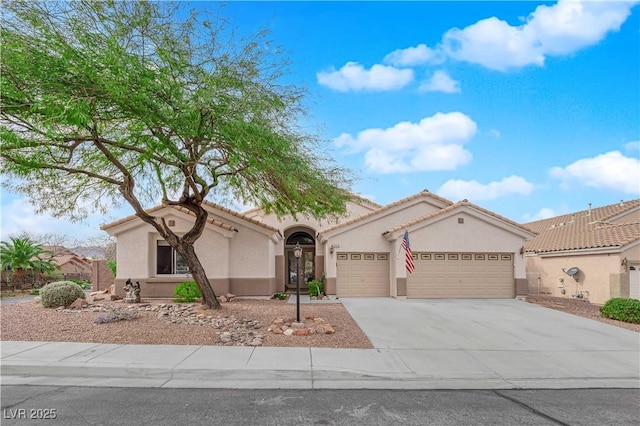 mediterranean / spanish home featuring concrete driveway, a tile roof, an attached garage, and stucco siding