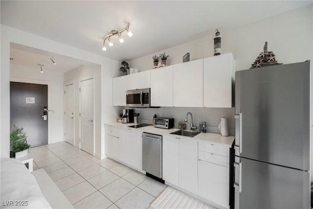 kitchen featuring stainless steel appliances, white cabinetry, sink, and light tile patterned floors