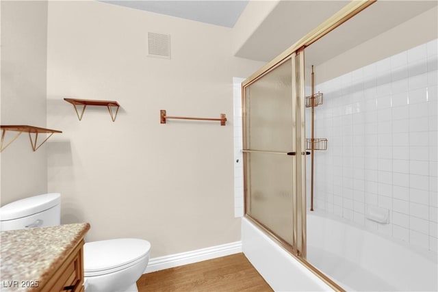 full bathroom featuring shower / bath combination with glass door, wood-type flooring, toilet, and vanity