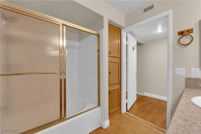 bathroom featuring vanity, hardwood / wood-style flooring, and combined bath / shower with glass door