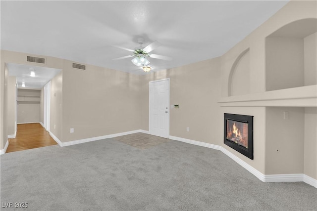 unfurnished living room featuring a fireplace, ceiling fan, and carpet flooring