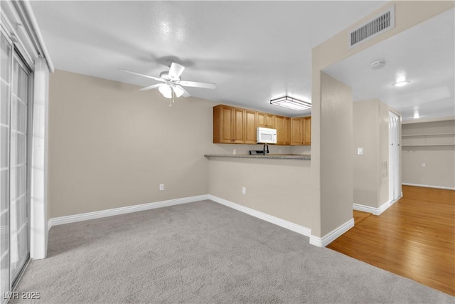 kitchen with ceiling fan, kitchen peninsula, and light carpet