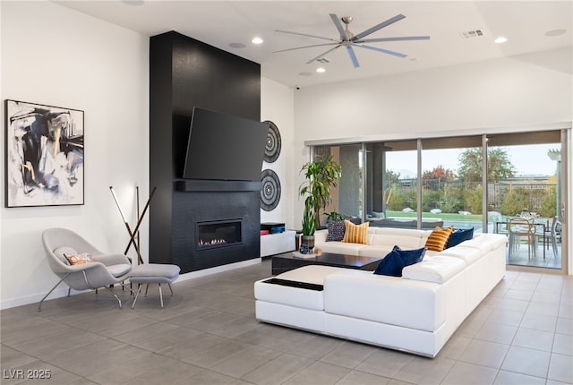 living room with a large fireplace, light tile patterned floors, and ceiling fan