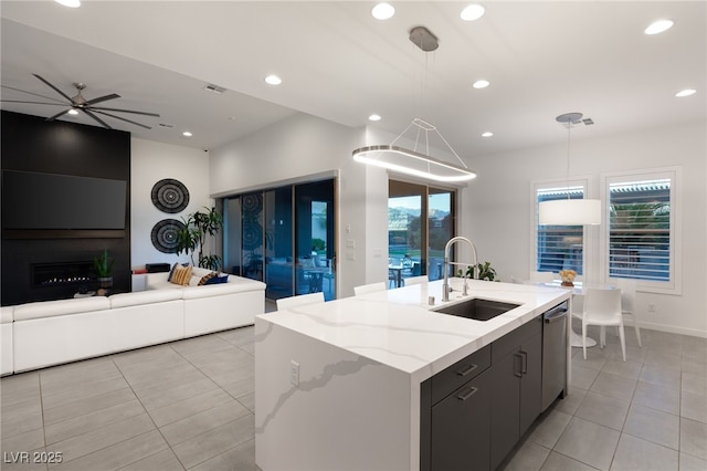 kitchen featuring pendant lighting, sink, dishwasher, an island with sink, and light tile patterned flooring