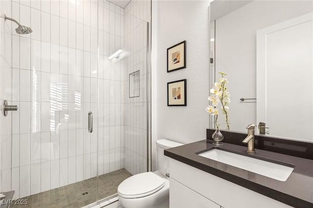 bathroom with vanity, a shower with shower door, and toilet