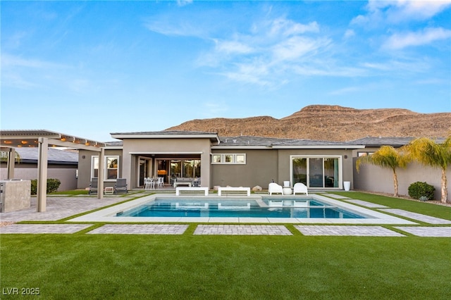 rear view of property featuring a mountain view, a lawn, and a patio area