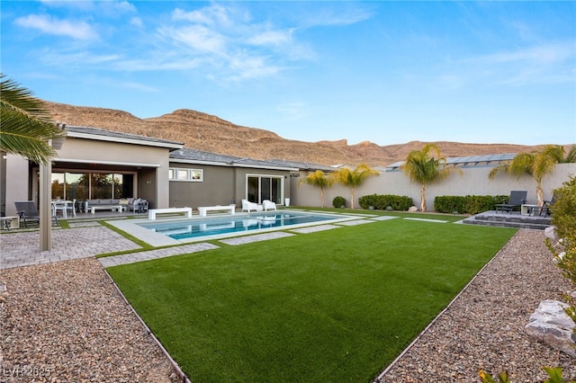 back of house featuring a mountain view, a lawn, and a patio