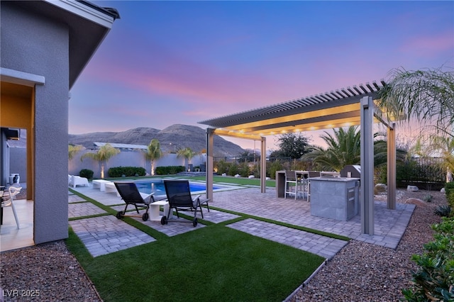 yard at dusk featuring a mountain view, a pergola, and a patio area