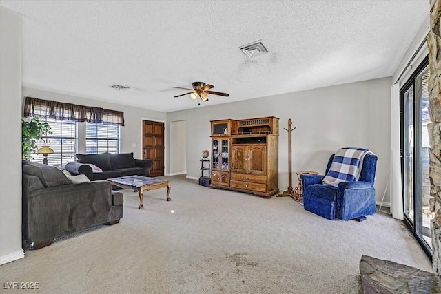 carpeted living room with ceiling fan and a textured ceiling