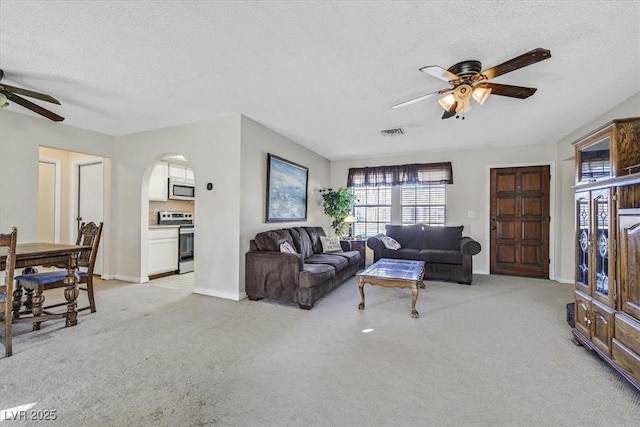 living room with ceiling fan, light colored carpet, and a textured ceiling