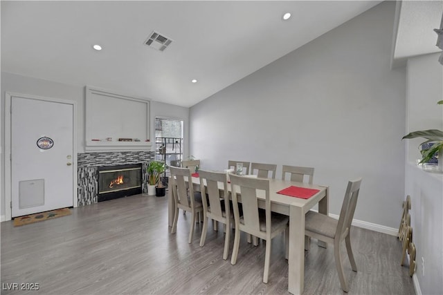 dining area with lofted ceiling, light hardwood / wood-style floors, and a tile fireplace