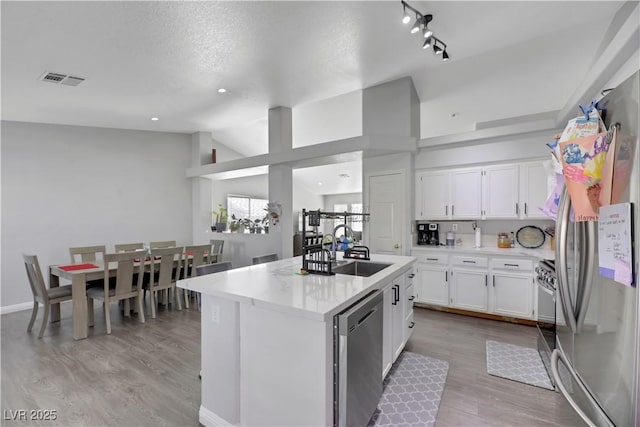 kitchen featuring vaulted ceiling, appliances with stainless steel finishes, sink, white cabinets, and a center island