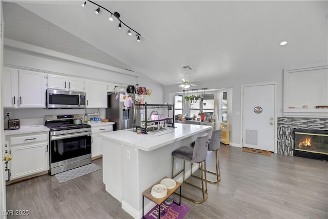 kitchen featuring stainless steel appliances, an island with sink, white cabinets, and a breakfast bar