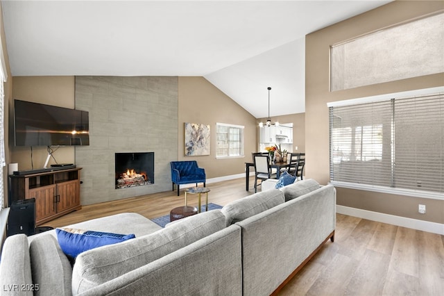 living room with a tile fireplace, wood-type flooring, a notable chandelier, and high vaulted ceiling