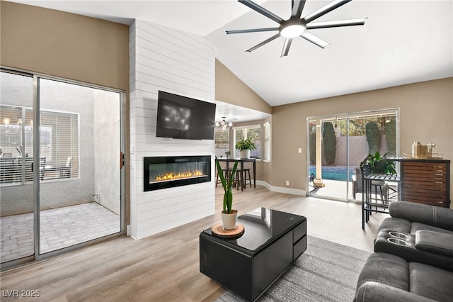 living room featuring light hardwood / wood-style flooring, a fireplace, lofted ceiling, and a healthy amount of sunlight