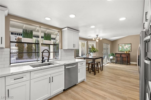 kitchen featuring white cabinetry, sink, stainless steel dishwasher, light stone countertops, and light hardwood / wood-style flooring