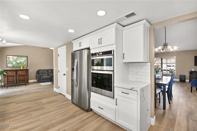 kitchen featuring stainless steel appliances, white cabinetry, light hardwood / wood-style floors, and decorative backsplash