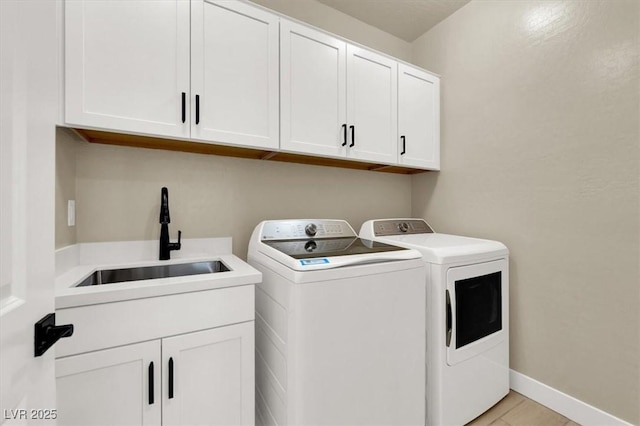 washroom with cabinets, separate washer and dryer, and sink