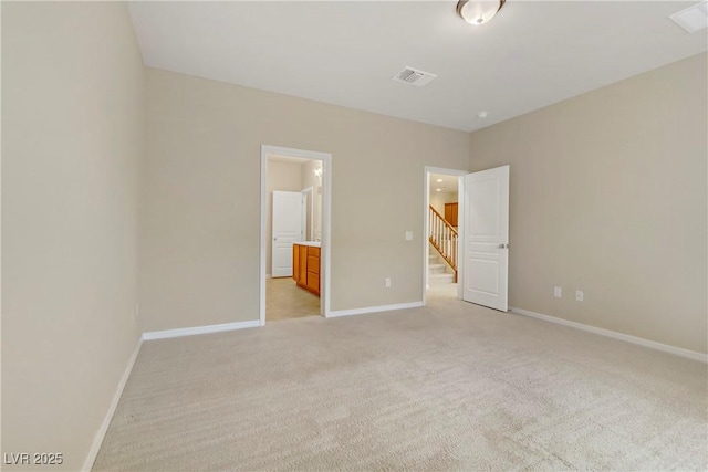 unfurnished bedroom featuring connected bathroom and light carpet