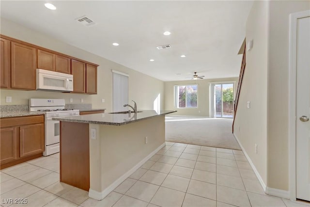 7659 Dewy Falls Ave, Las Vegas, NV 89179 - kitchen featuring white appliances, a sink, light tile patterned floors, a kitchen island with sink, and brown cabinetry