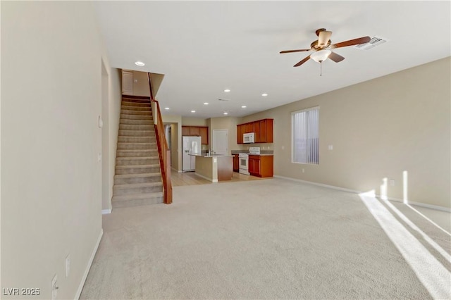 unfurnished living room featuring light carpet and ceiling fan