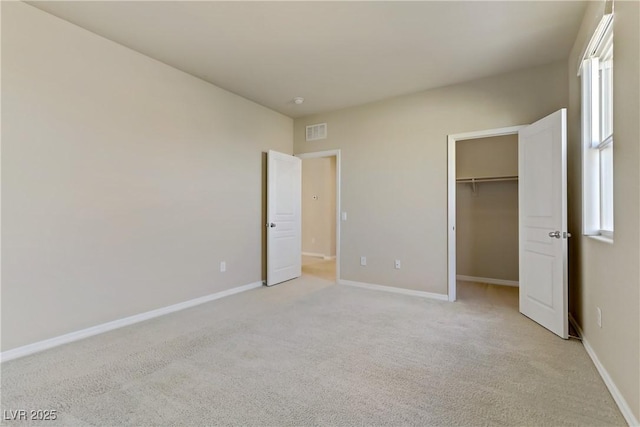 unfurnished bedroom with multiple windows, a spacious closet, a closet, and light carpet