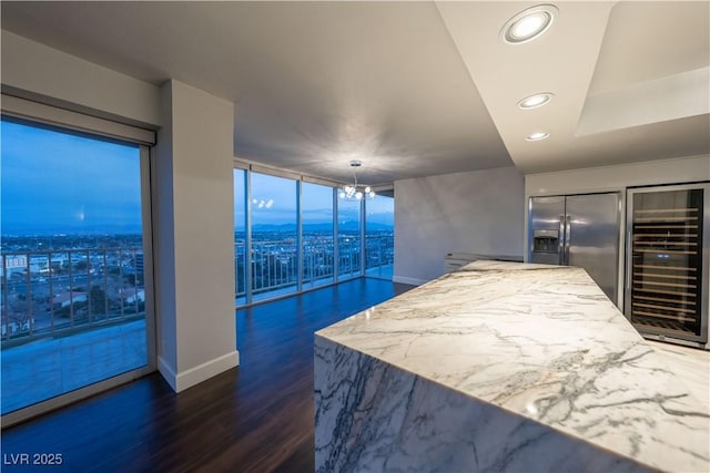 kitchen with hanging light fixtures, dark hardwood / wood-style floors, stainless steel refrigerator with ice dispenser, light stone counters, and beverage cooler