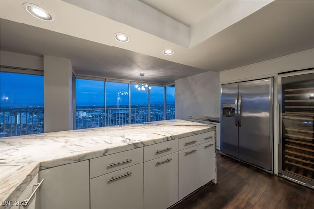 kitchen featuring white cabinetry, dark hardwood / wood-style floors, stainless steel fridge, and light stone counters