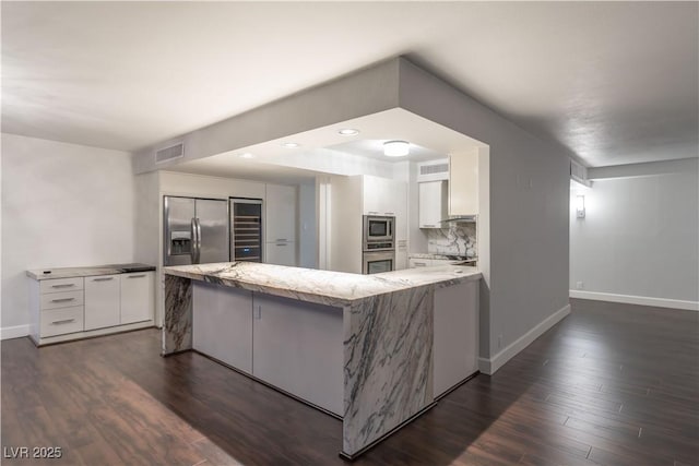 kitchen featuring white cabinetry, dark hardwood / wood-style flooring, kitchen peninsula, and appliances with stainless steel finishes