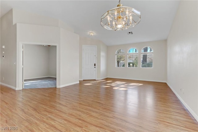 interior space with vaulted ceiling, a chandelier, and light hardwood / wood-style flooring