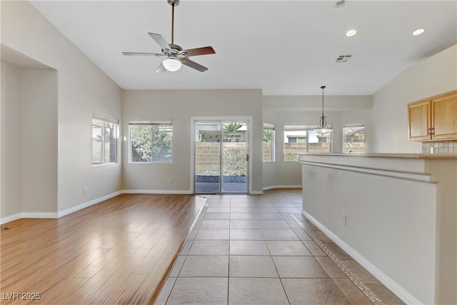 interior space with ceiling fan, lofted ceiling, and light tile patterned floors