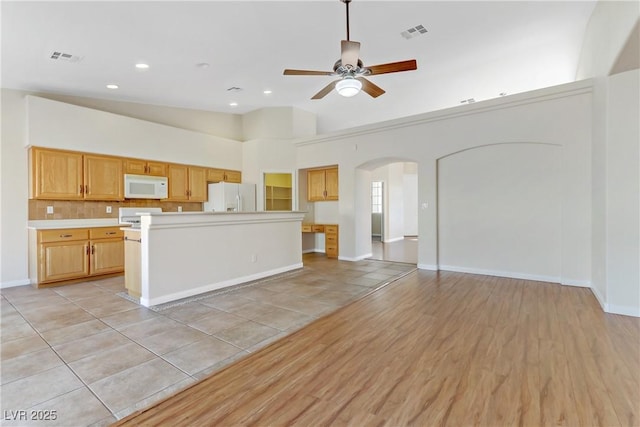 kitchen featuring white appliances, light wood-type flooring, a kitchen island, ceiling fan, and decorative backsplash