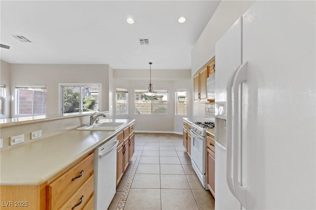 kitchen with sink, decorative light fixtures, light tile patterned floors, a wealth of natural light, and white appliances