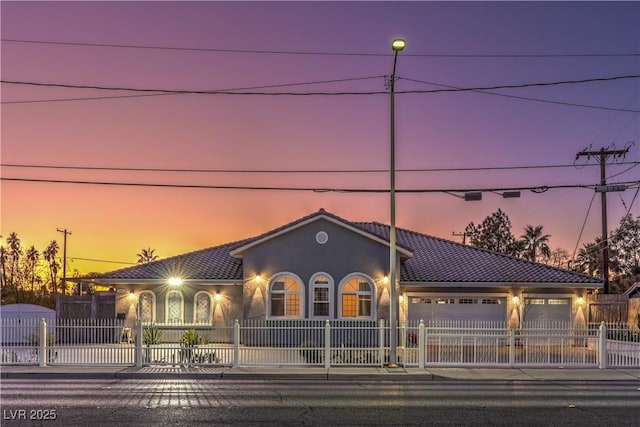 view of front of home with a tiled roof, a fenced front yard, an attached garage, and stucco siding