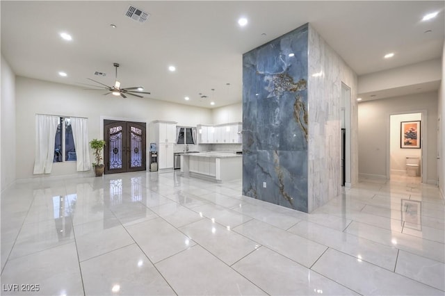 unfurnished living room with french doors, ceiling fan, and tile walls