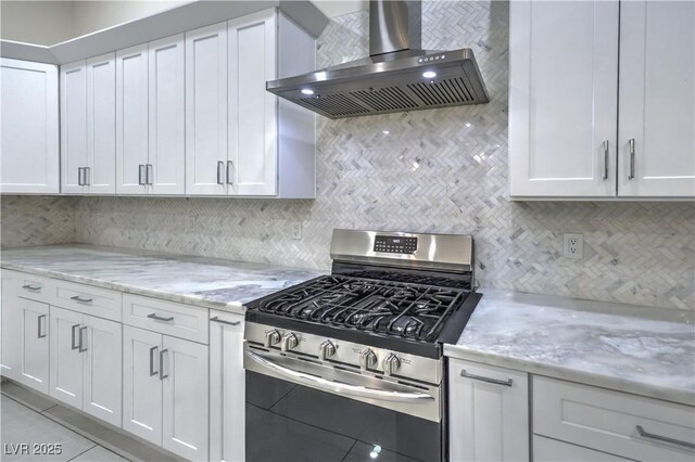 kitchen with light stone counters, decorative backsplash, white cabinets, gas range, and exhaust hood