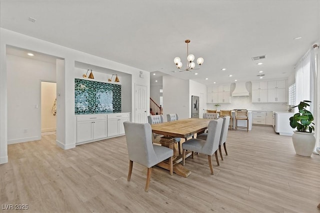 dining space with an inviting chandelier and light hardwood / wood-style flooring