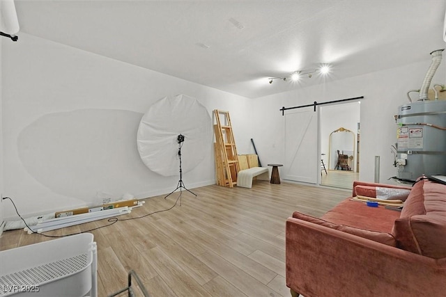 living room featuring water heater, light hardwood / wood-style flooring, and a barn door