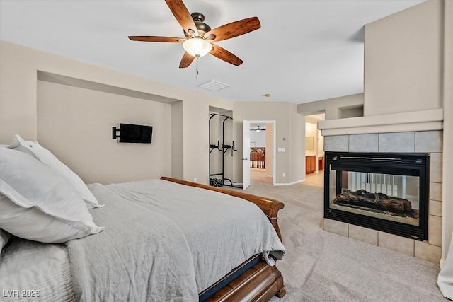 carpeted bedroom with ceiling fan, ensuite bath, and a fireplace