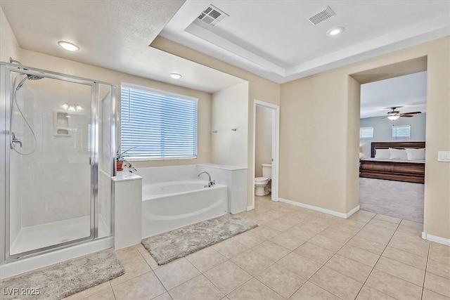 bathroom featuring tile patterned floors, toilet, separate shower and tub, a raised ceiling, and ceiling fan