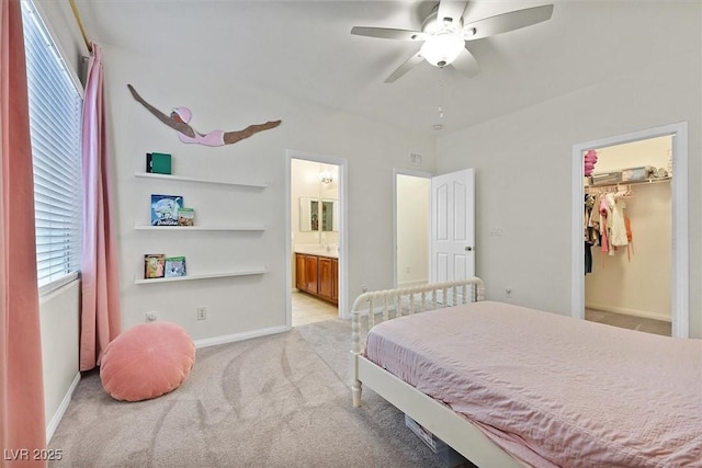 carpeted bedroom featuring ceiling fan, a walk in closet, and ensuite bath