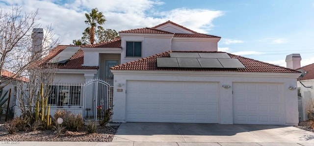 mediterranean / spanish-style house featuring an attached garage, solar panels, a tiled roof, driveway, and stucco siding