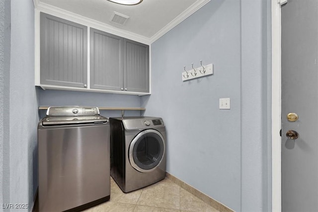 laundry room featuring light tile patterned floors, crown molding, washing machine and dryer, and cabinets