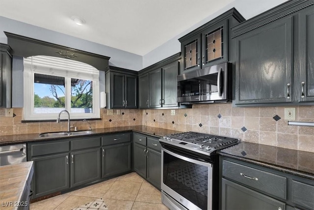 kitchen with light tile patterned flooring, wood counters, sink, decorative backsplash, and stainless steel appliances